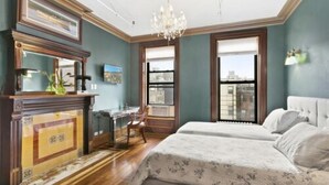 A bedroom with a large bed, a desk, and a chandelier. - Northern Lights Mansion (New York)