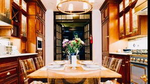 A dining area with a long table, clear chairs, wooden cabinets, and a vase of flowers. - Northern Lights Mansion (New York)