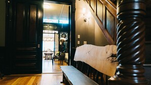 A wooden bench in a hallway with a view into a dining area. - Northern Lights Mansion (New York)