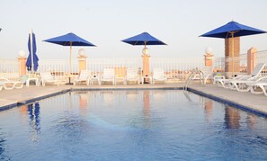 Una piscina al aire libre, sillones reclinables de piscina