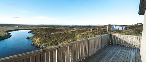 Una terraza de madera con vista a un río y colinas distantes.
