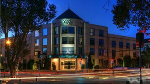 A multi-story hotel with a prominent rooftop sign, a well-lit entrance, and a street view with traffic lights and a pedestrian crossing. - Hotel Costa Real (La Serena)