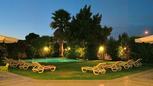 A pool area with lounge chairs and a palm tree. - Hotel Costa Real (La Serena)