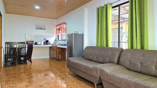 A living room with a sofa and a dining area with chairs and a table.