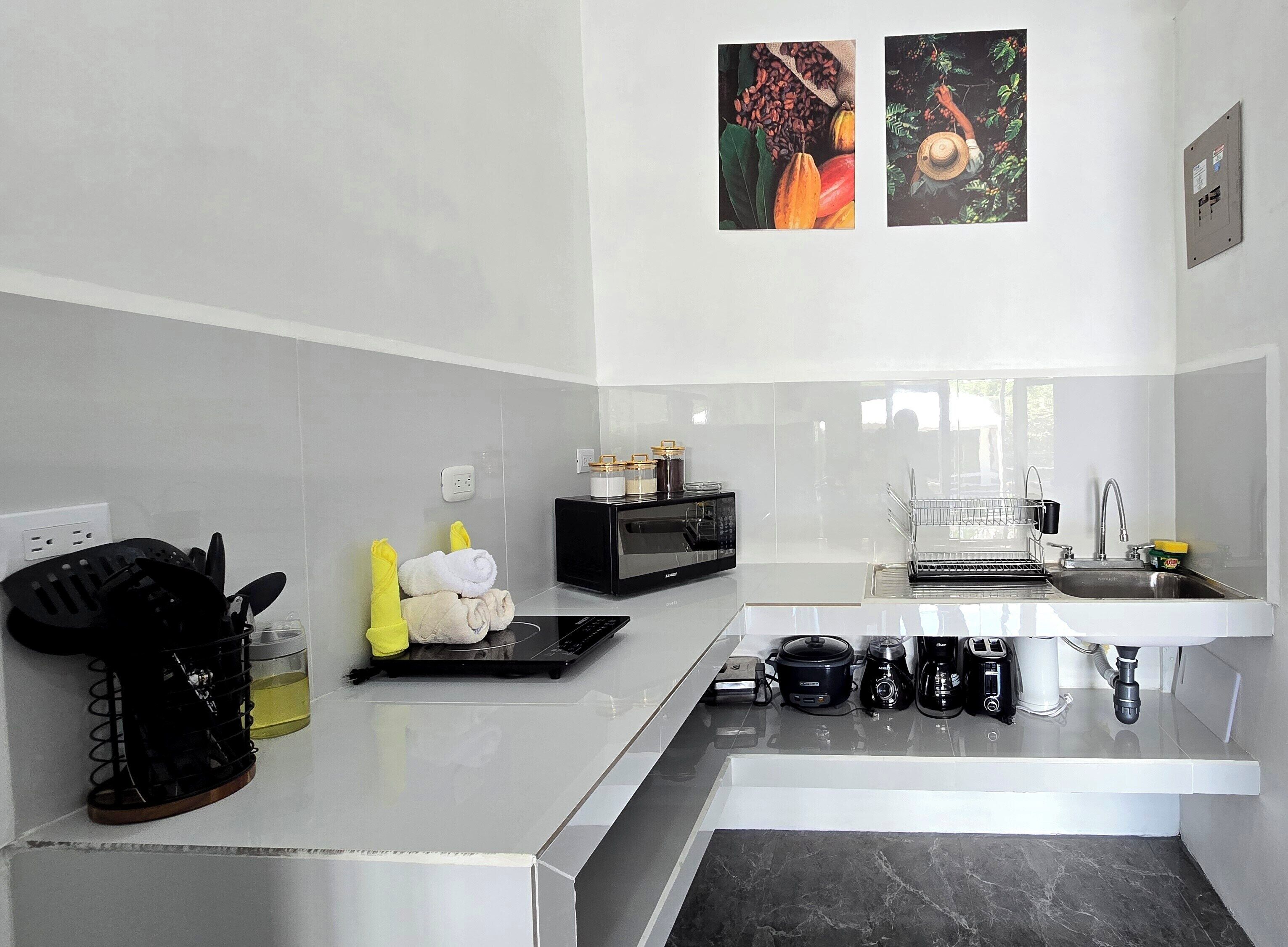 Cocina moderna con microondas, tostadora y cafetera. Hay toallas y utensilios en la encimera.