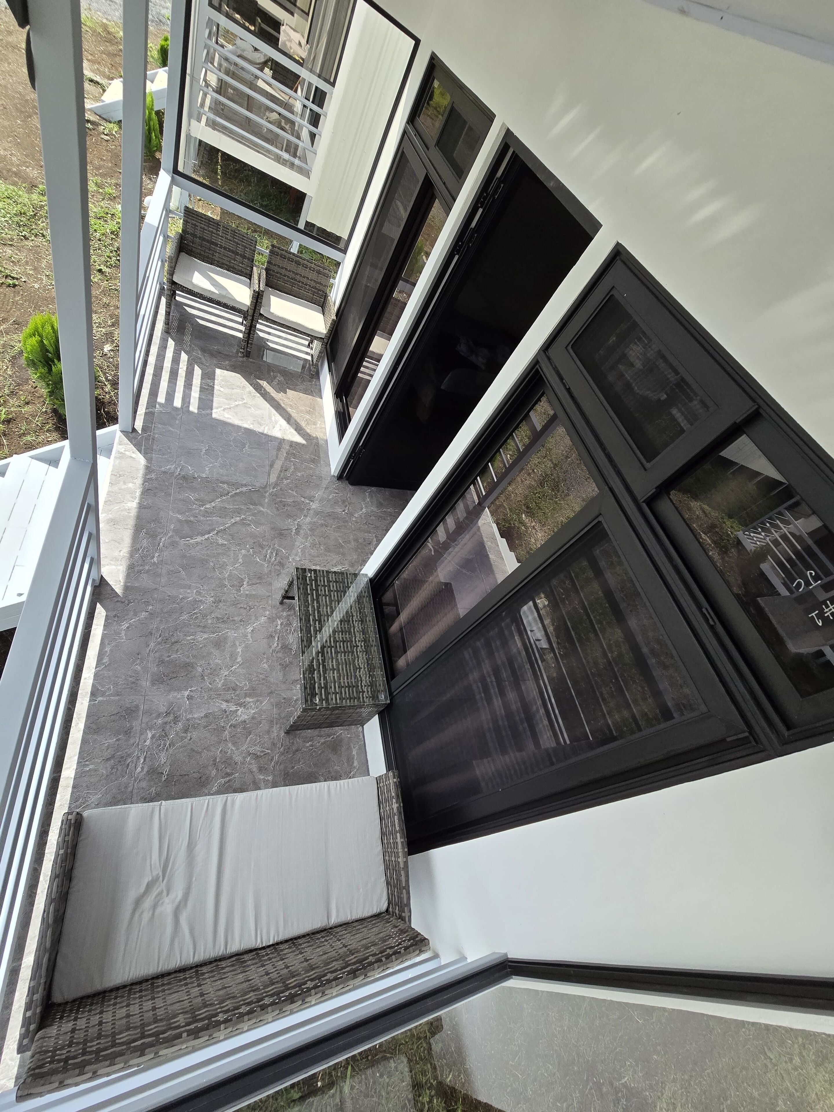 A modern building with a covered outdoor area, large windows, and a tiled floor.