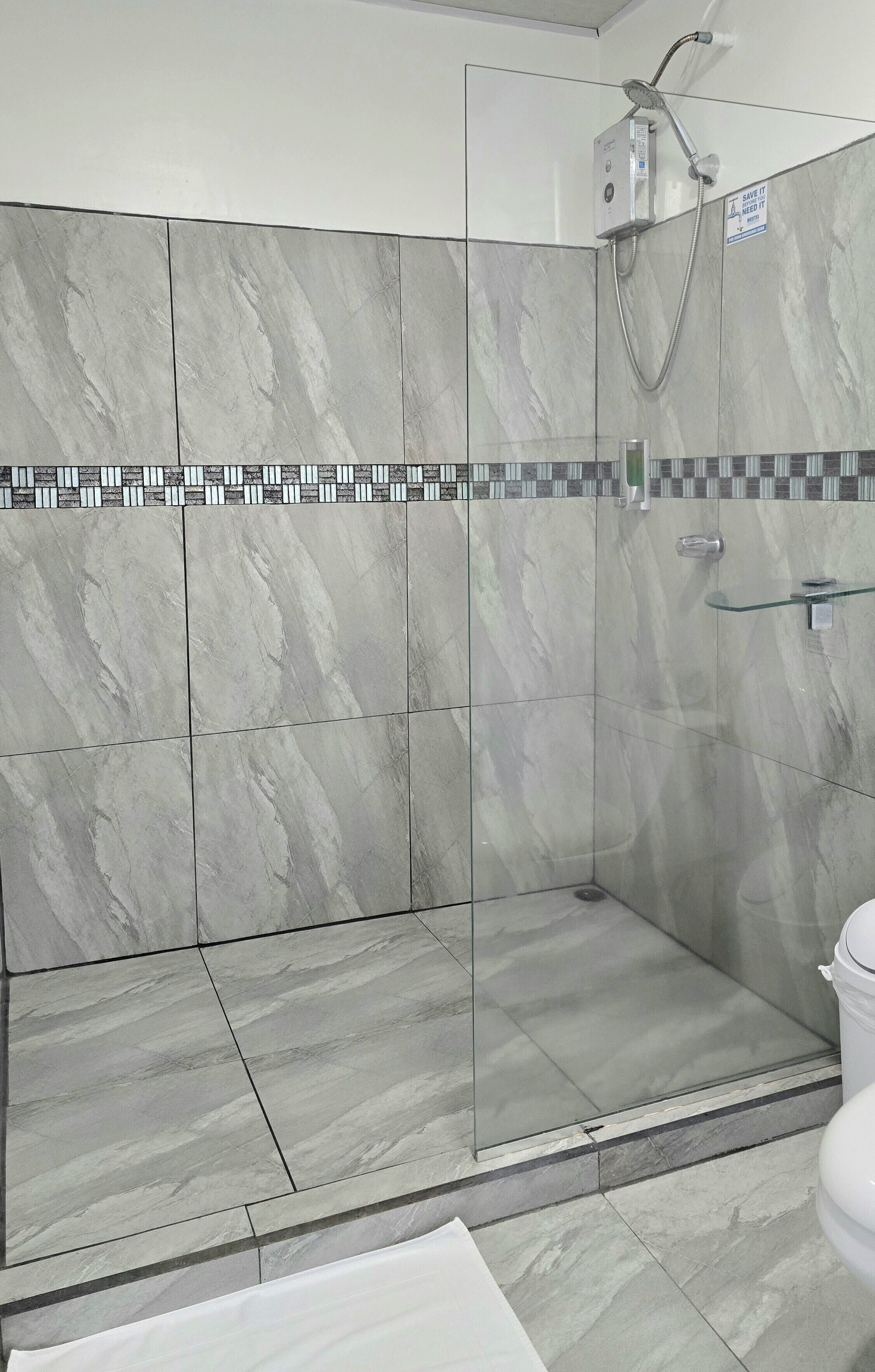A shower area with a glass door, tiled walls, and a showerhead.