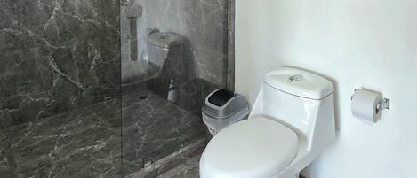 A bathroom with a toilet, a shower, and a marble floor.
