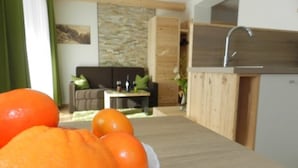 A modern kitchen with a wooden countertop, a sink, and a dining area with a table and chairs. - Garni Apartments Mezdi (Selva di Val Gardena)