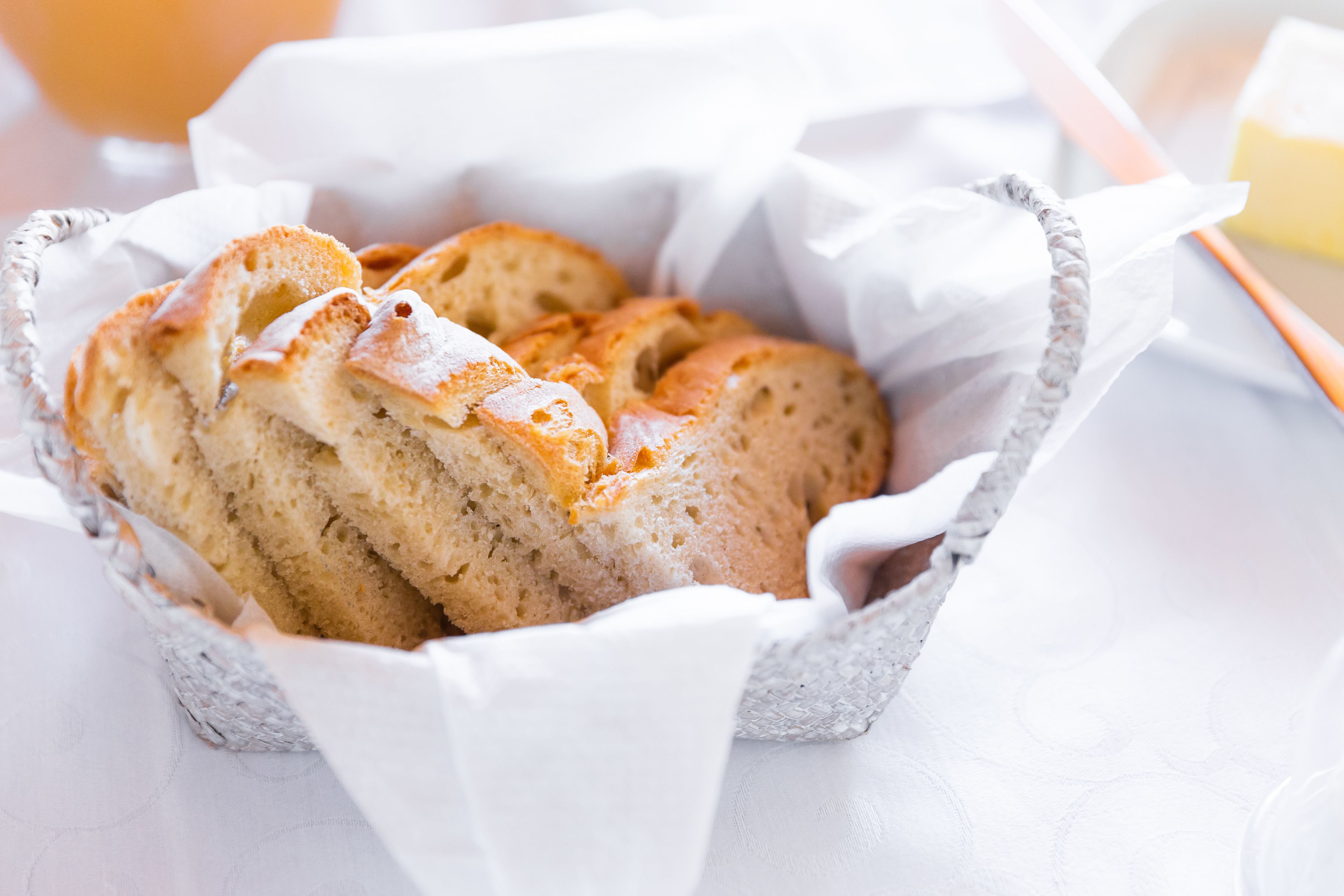 A basket of freshly baked bread with a golden crust, placed on a white cloth.