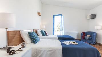 Una camera d'albergo con due letti, una scrivania, una sedia, una TV e una finestra con vista.