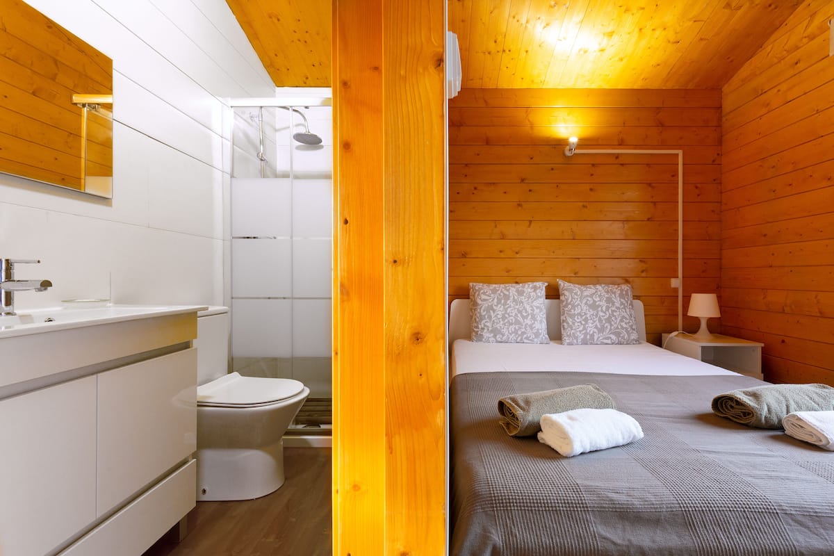 A wooden cabin-style room with a bathroom and a bed.