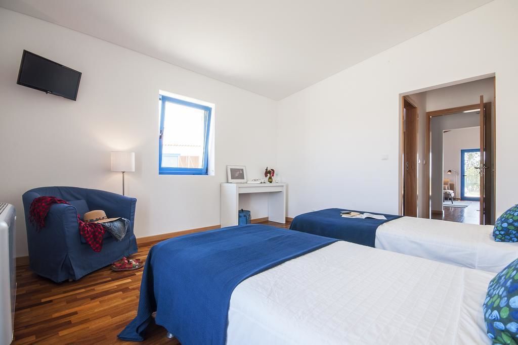 A bedroom with two beds, a desk, a TV, and a window.