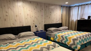 Un dormitorio con dos camas, una mesita de noche, un aparador y una ventana con cortinas.