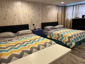 Ein Schlafzimmer mit zwei Betten, einem Nachttisch, einer Kommode und einem Fenster mit Vorhängen.