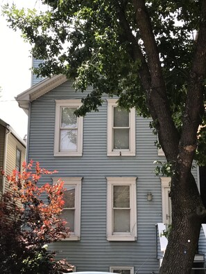 Una casa de dos pisos con un árbol grande en el frente.