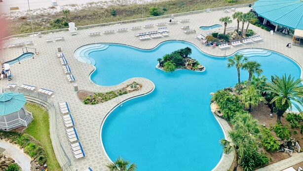 Ein Resort mit großem Swimmingpool, Liegestühlen und Strandabschnitt.