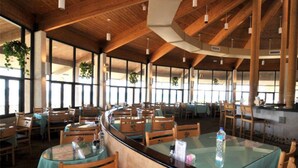 Ein Restaurant mit Holzbalken, Glastischen und Stühlen.