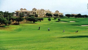 Un campo de golf con un edificio grande al fondo.