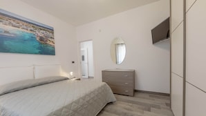 A bedroom with a bed, a dresser, a mirror, and a TV. - Angela Rosa House (Carovigno)