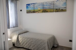 A bedroom with a bed, a window with curtains, and a wall with a landscape painting. - Angela Rosa House (Carovigno)