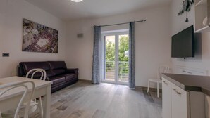 A modern living room with a sofa, a dining table, a TV, and a balcony with a view. - Angela Rosa House (Carovigno)