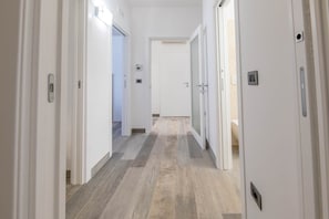 A corridor with white doors, a light switch, and a thermostat on the wall. - Angela Rosa House (Carovigno)