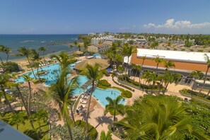 A resort with multiple swimming pools, palm trees, and a view of the ocean. - CONDO HOTEL, DORADO (WITH LIVING ROOM/ DINNING ROOM / KITCHEN) (Higuillar)