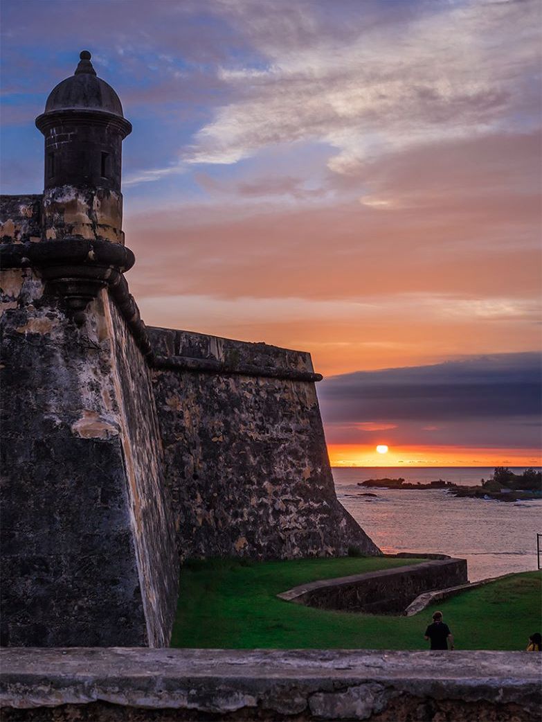 A historic fort with a watchtower, a flagpole, and a flag.