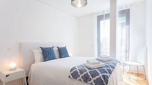 A neatly arranged bedroom with a bed, bedside table, and chair, featuring a simple, clean design.