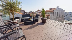 A rooftop terrace with outdoor seating, a potted plant, and a view of the cityscape.