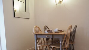 Ein Essbereich mit einem Holztisch und Stühlen, einer wandmontierten Leuchte und einem gerahmten Bild an der Wand.