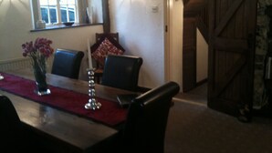 A dining area with a wooden table, chairs, a vase of flowers, and a red runner.