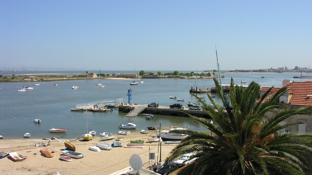 A coastal marina with boats docked, a sandy beach, and a clear view of the sea. - THE BOAT - Themed Apartment (Seixal)