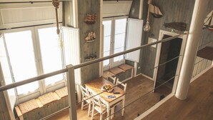 A dining area with a wooden table and chairs, a bench, and a view of the kitchen. - THE BOAT - Themed Apartment (Seixal)