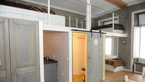 A loft-style bedroom with a loft bed, a small kitchenette, and a bathroom. - THE BOAT - Themed Apartment (Seixal)