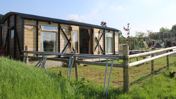 A wooden building with large windows and a metal fence in front. - Greenacres Self Catering Railway Wagon-Glamping (Bridport)
