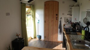 A kitchen with wooden cabinets, a sink, and a window with curtains. - Greenacres Self Catering Railway Wagon-Glamping (Bridport)