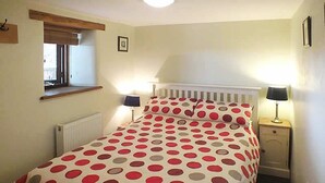 A bedroom with a bed, bedside lamps, a window, and a radiator. - Keepers Cottage - sleeps 2 adults, 2 children and your dogs (Cornwall)