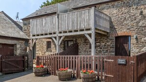 A stone building with a wooden balcony and a gated entrance. - Keepers Cottage - sleeps 2 adults, 2 children and your dogs (Cornwall)