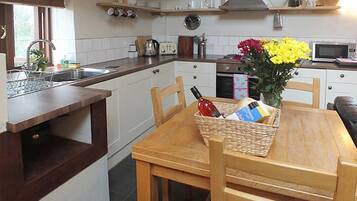 A kitchen with a wooden table, chairs, a microwave, and a sink.