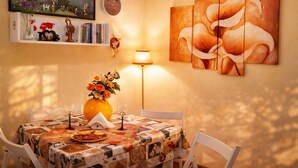 Ein Essbereich mit einem Tisch für zwei Personen, einer Blumenvase und einem Blumenbild an der Wand.