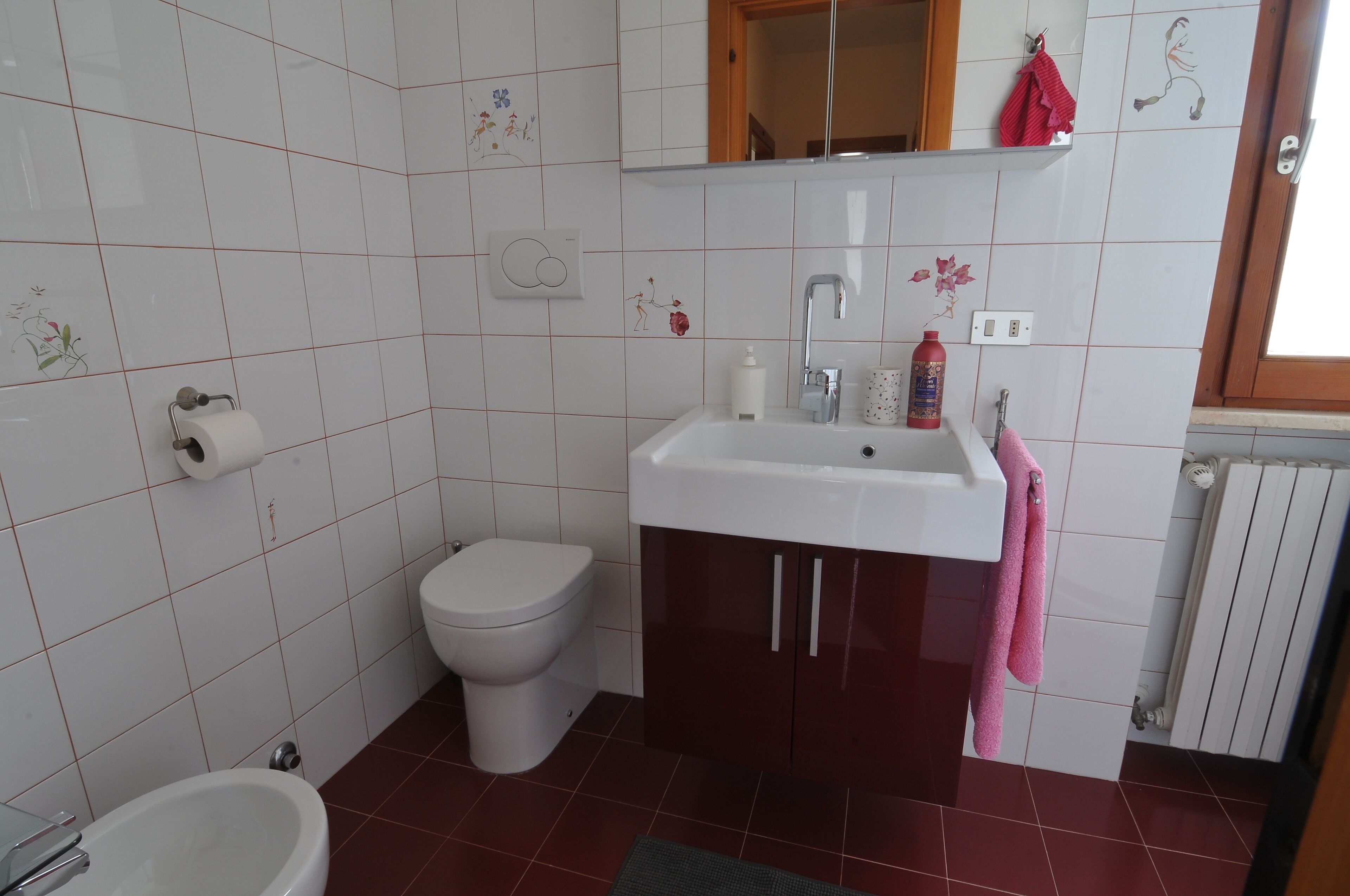 A bathroom with a toilet, sink, and mirror.