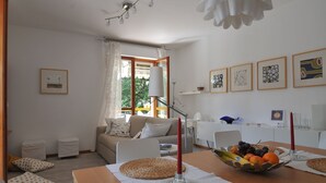 Een moderne woonkamer met een bank, eettafel en kunstwerken aan de wanden.