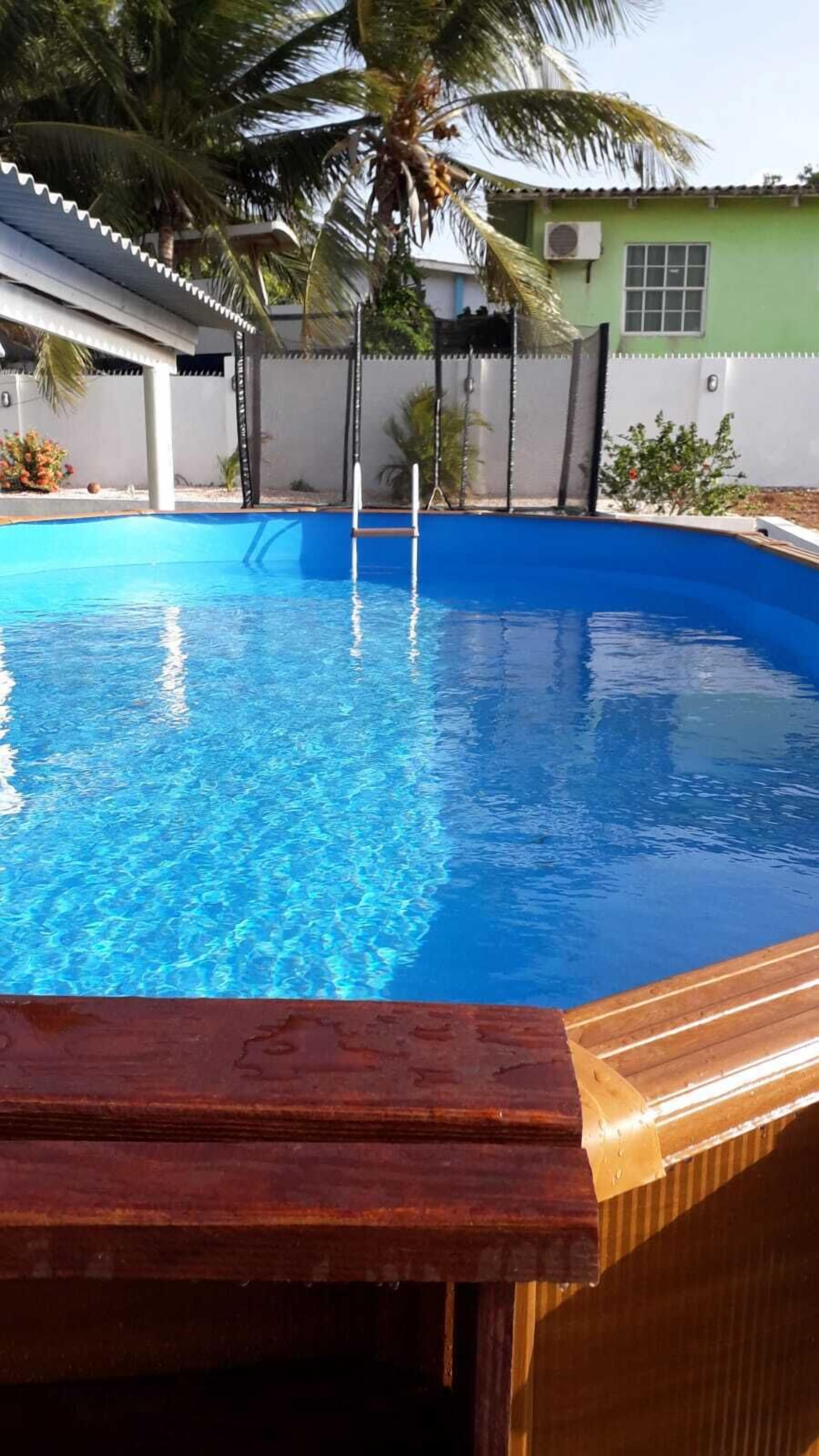 A swimming pool with a wooden deck in the foreground.