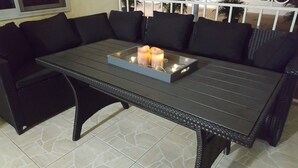 Un sofá oscuro con cojines negros y una mesa rectangular con una bandeja que sostiene dos velas.