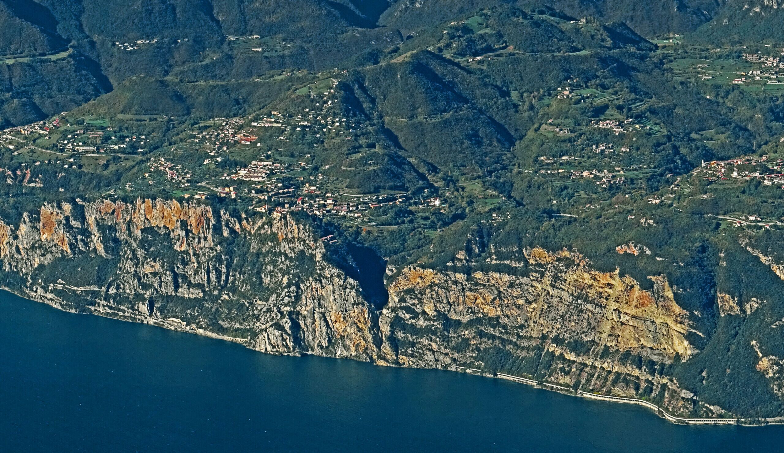 A coastal town with a rugged coastline, terraced fields, and a train track along the shore.