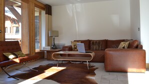 Un salon moderne avec un canapé en cuir, une table basse en bois et un pouf en cuir.