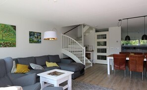 A modern living room with a grey sofa, a white coffee table, and a staircase leading to a kitchen area.