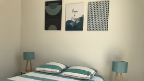 Un dormitorio con una cama, dos mesitas de noche, una lámpara en cada una y tres cuadros colgados en la pared.